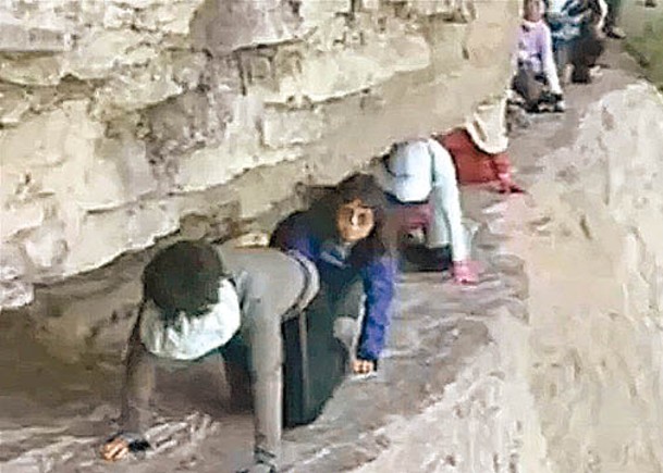 遊客在無保護措施下狗爬式過懸崖。