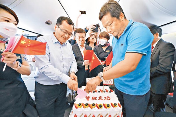 旅客在飛機客艙內切下首航慶祝蛋糕。（中新社圖片）