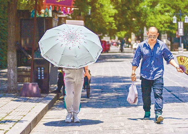 遊客手持遮陽傘行走在山東省青州市古城景區。（中新社圖片）