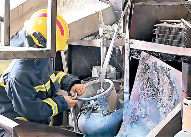消防員檢查燒烤店內的液化石油氣罐。