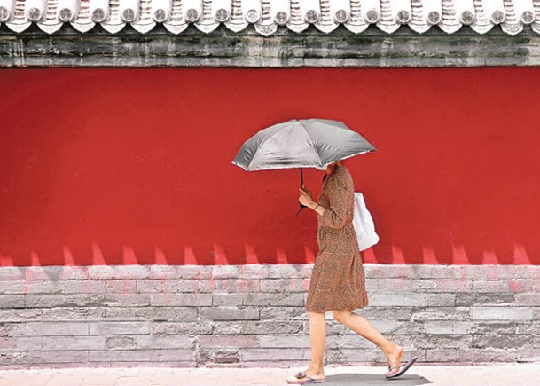 在北京鼓樓外，行人以雨傘遮擋烈日。（中新社圖片）