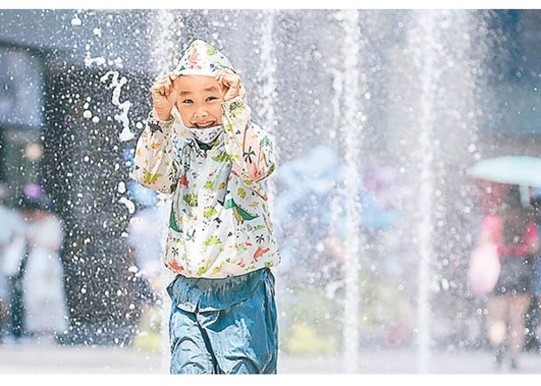 北京高溫持續，小朋友在街頭噴泉玩耍。（中新社圖片）