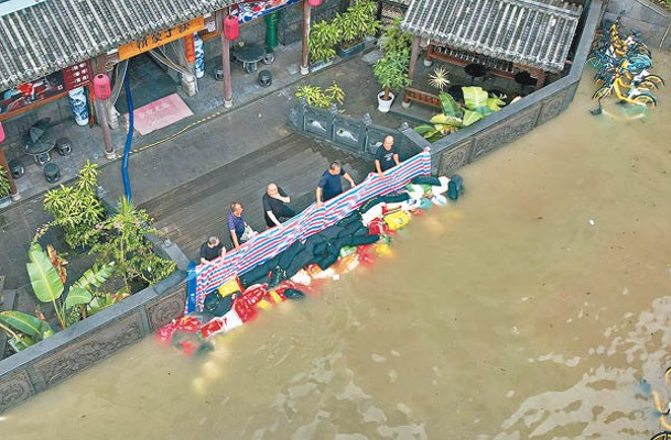 福州餐館職員合力阻止洪水湧入。（中新社圖片）
