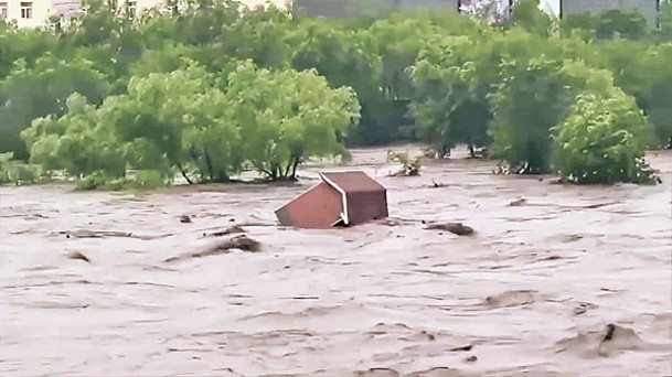 北京市阜石路跨永定河大橋下水流湍急，有簡易房屋被沖進河流。