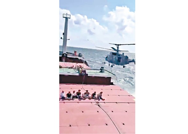 俄羅斯卡29直升機飛近貨輪Sukru Okan號，有船員坐在甲板上。