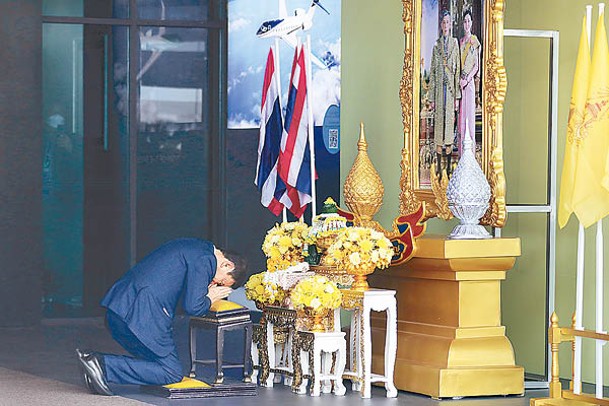 他信在廊曼國際機場向泰王與王后的畫像鞠躬。（Getty Images圖片）