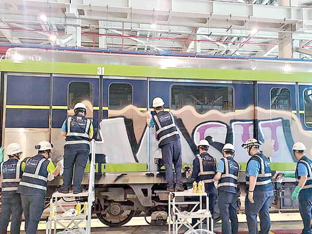 台中捷運工人忙於清潔被塗鴉的車廂。