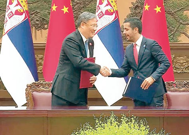 王文濤（左）與莫米洛維奇（右）簽署自貿協定後握手。