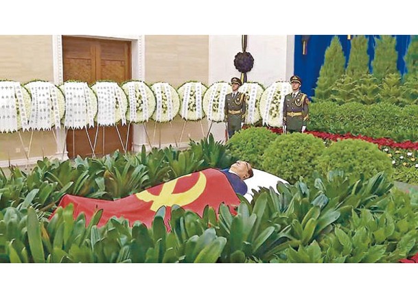李克強的遺體被鮮花翠柏叢包圍，身上覆蓋中共黨旗。
