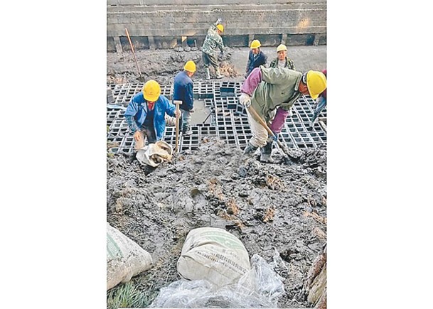 工人把磚材鋪在河底。