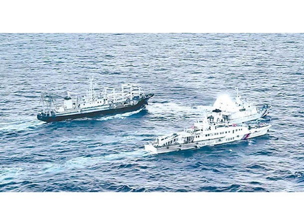 中國海警船（下）發射水炮阻止菲律賓船隻（中）。