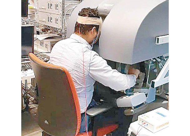 參與者坐在手術機械人控制台前接受測試。