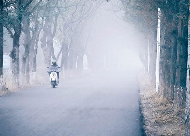 北京：一輛電單車在霧中出行。