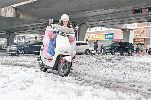 河南鄭州民眾在積雪道路出行。（中新社圖片）