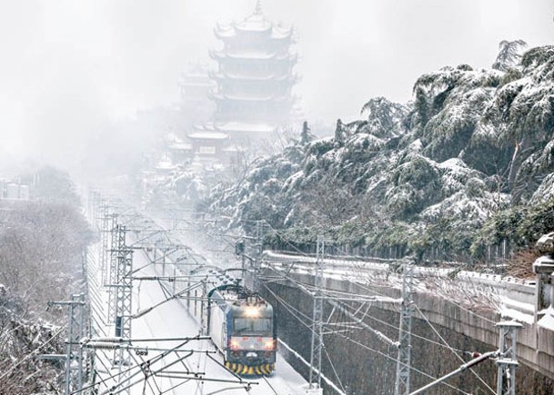 湖北武漢下雪，列車雪中從武漢黃鶴樓旁駛過。（中新社圖片）