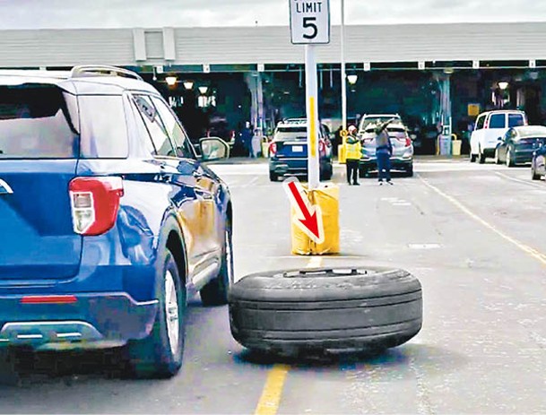 輪胎（箭嘴示）墜落在機場的停車場，砸毀地面汽車。