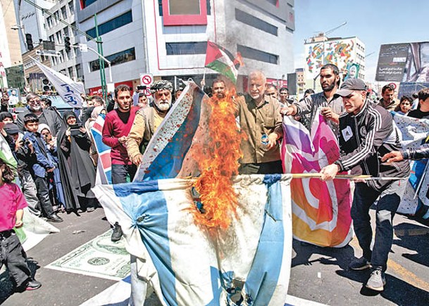 伊朗民眾在德黑蘭集會中焚燒美以兩國旗幟。（Getty Images圖片）