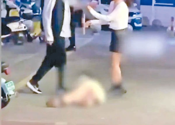 男子用腳踢打躺地上的女子。