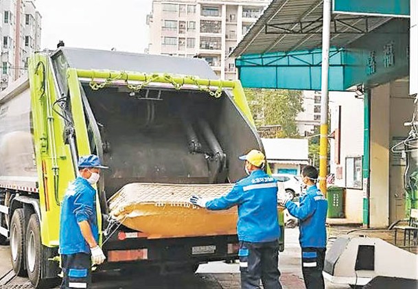 廣東江門一輛環境服務公司的破碎壓縮車正等待工作人員將垃圾搬進車裏，進行初步壓縮。