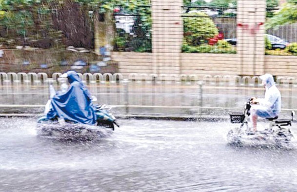 民眾駕電動單車涉水而過。