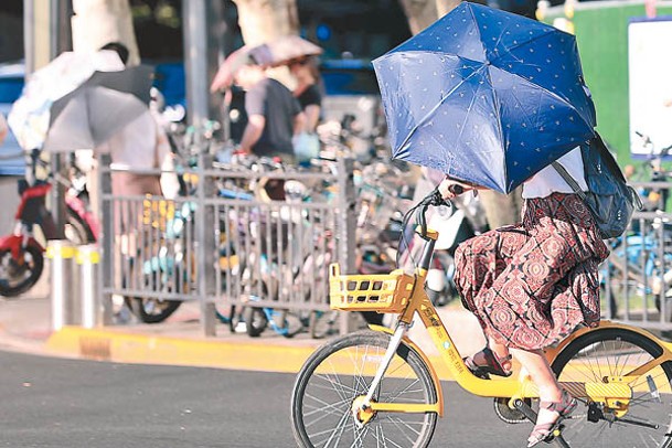 夏日炎炎，上海市民打傘出行。（中新社圖片）