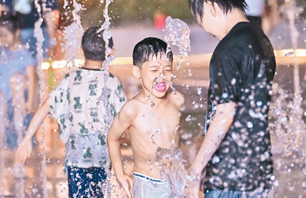 江蘇淮安兒童在街頭噴泉戲水消暑。（中新社圖片）