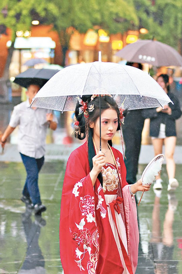 穿古裝的年輕人撐傘在雨中的城南景區參觀。（中新社圖片）