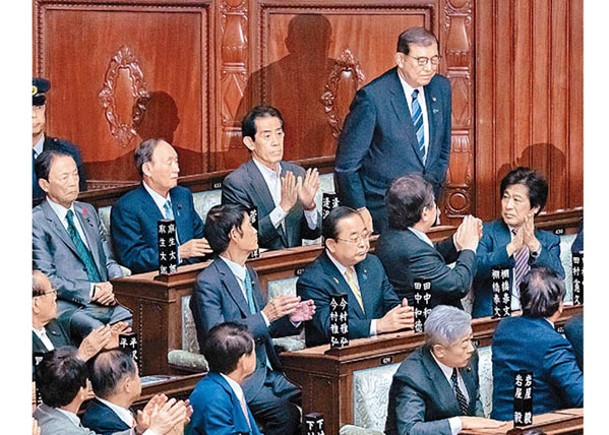 石破茂（後）當選首相後起立致意。