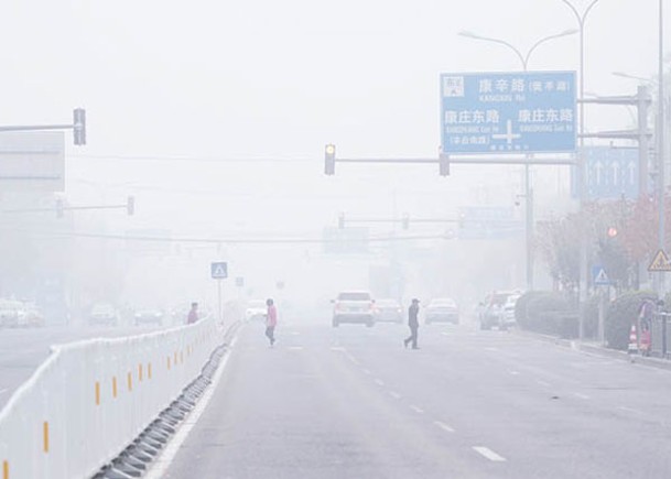 北京 ：市民在霧中出行。