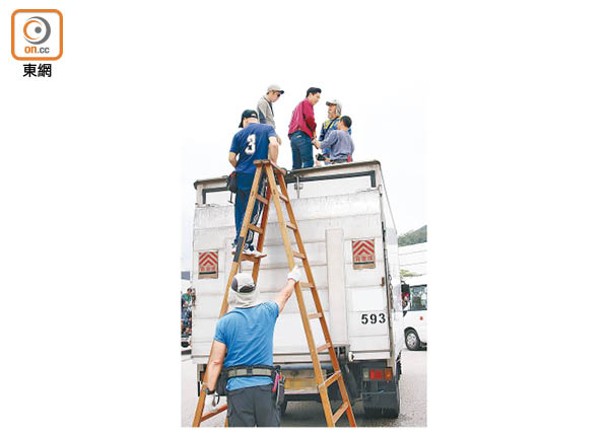 吳偉豪從木梯爬上貨車頂，工作人員替他繫上安全帶。