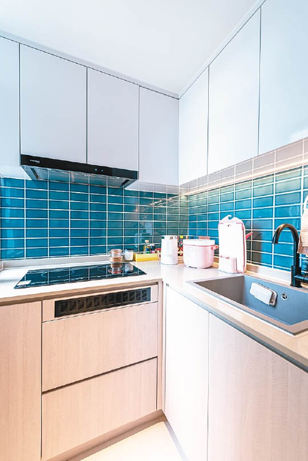 廚房採用了開放式設計，選用湖水藍色的日本瓷磚作牆飾，令客廳與廚房的分區更清晰。
