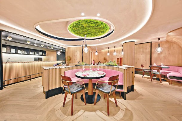 主用餐區以木材和翠綠色作主調，配珊瑚粉紅絨毛椅子及大理石餐桌，加上天花的苔蘚裝飾牆，簡約亮麗。