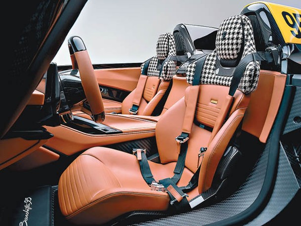 碳纖賽車座椅以啡色可持續豪華皮革及千鳥格高級織布包覆，配上4點式安全帶，特別強化腿部承托，帶來更高舒適性。
