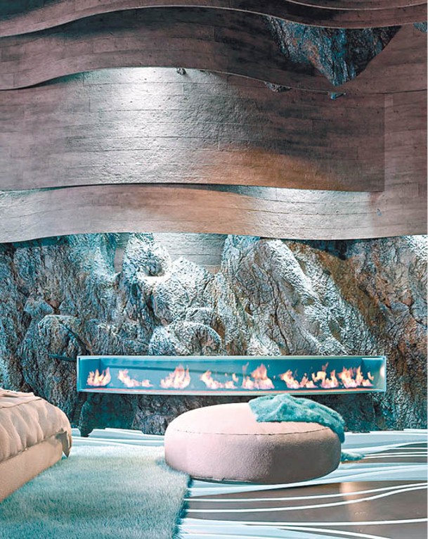 富有質感的岩石牆加設壁爐，為這個幽藍色空間添加幾分暖意。