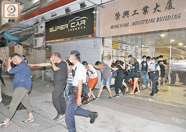 荃灣工廈被捕男女由警員押走。（胡德威攝）