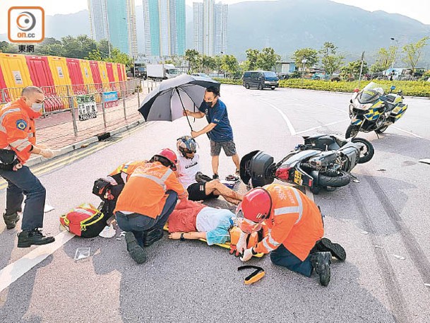 屯門：傷者或坐或臥接受包紮，有人在旁邊代為撐傘。 （文健雄攝）