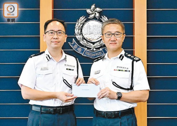 警務處處長蕭澤頤（右）頒授委任狀予梁世光（左）。