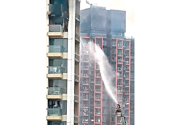 消防員升起雲梯射水灌救。