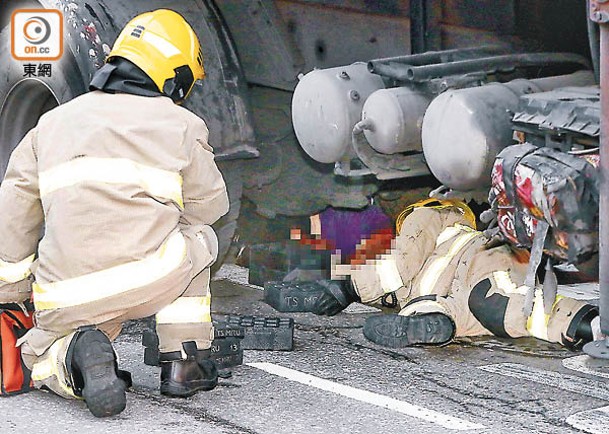 消防員在車底救出事主。（梁國雄攝）