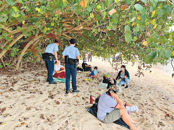 警員向沙灘上市民派發宣傳單張。