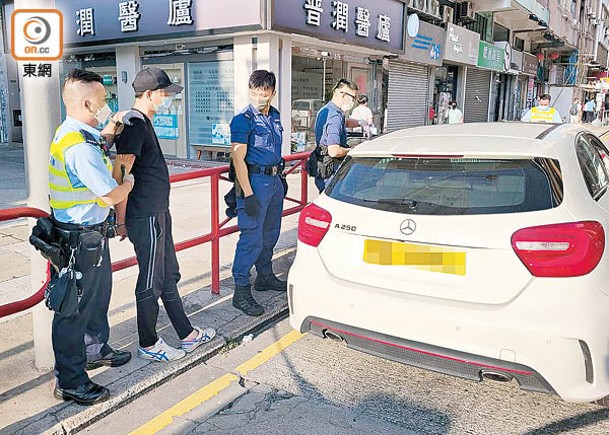 警員押解被捕司機搜查私家車。（余宏基攝）