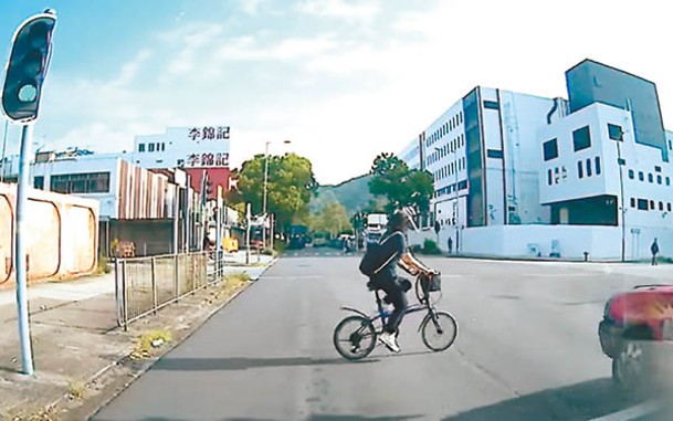 單車婦朝的士前方衝近。