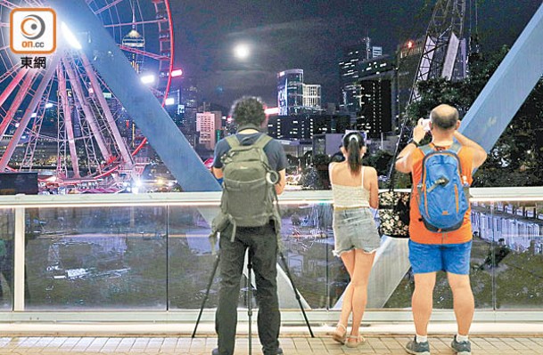 腳步急速的港人在行人天橋上駐足停留賞月。