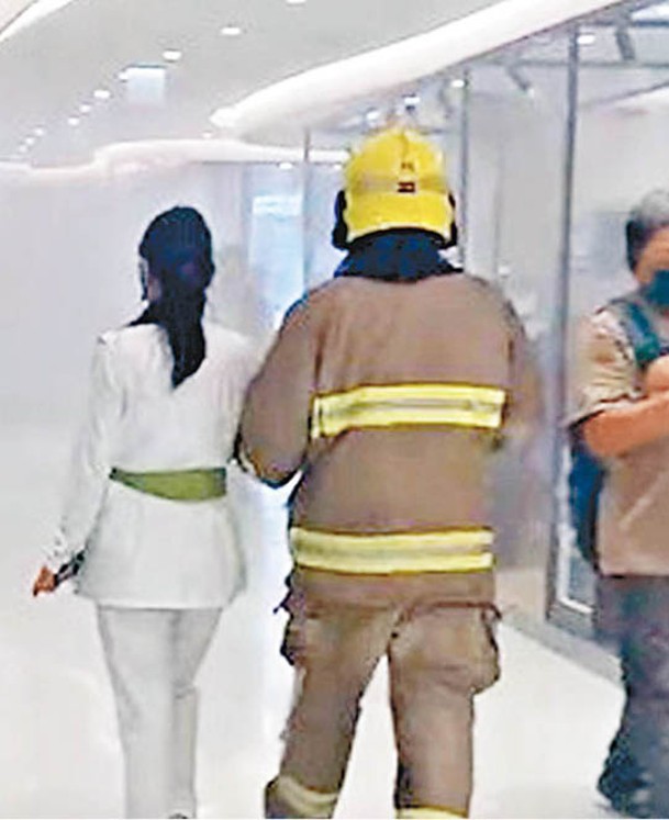 一名女子獲消防人員引領離開。