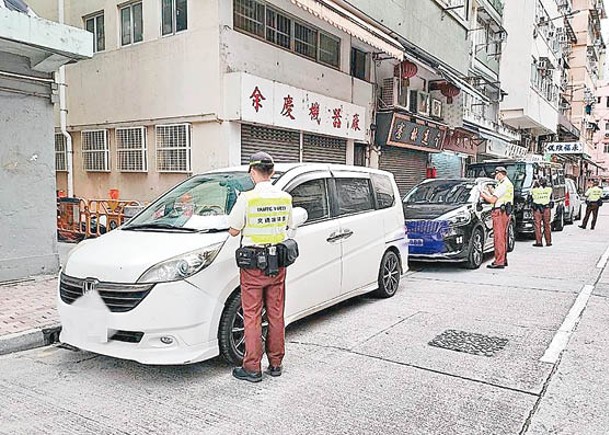 九龍城：人員向違泊車輛發出定額罰款通知書。