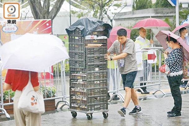 有展商職員冒雨推着貨品，打算提早收檔。