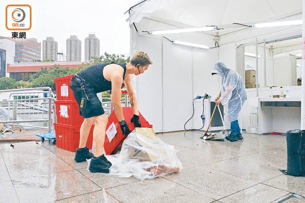 有展商職員在雨下狼狽運送貨物，有人因天雨關係弄翻商品。