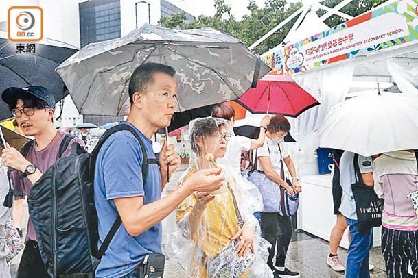 市集重開後，入場者撐着雨傘進食。