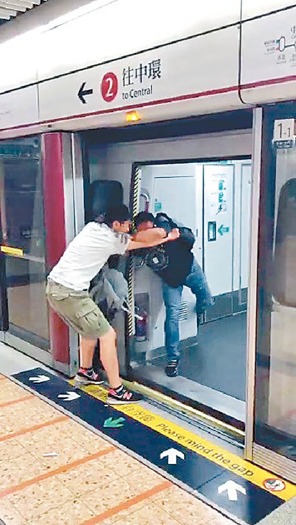 兩人在車廂與月台之間扭打。
