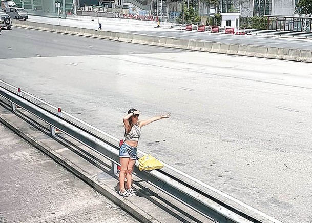 一名穿着火辣的女子在東隧巴士轉車站石壆圖截順風車。